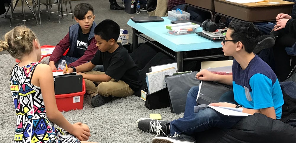 Students work together sitting on the carpet